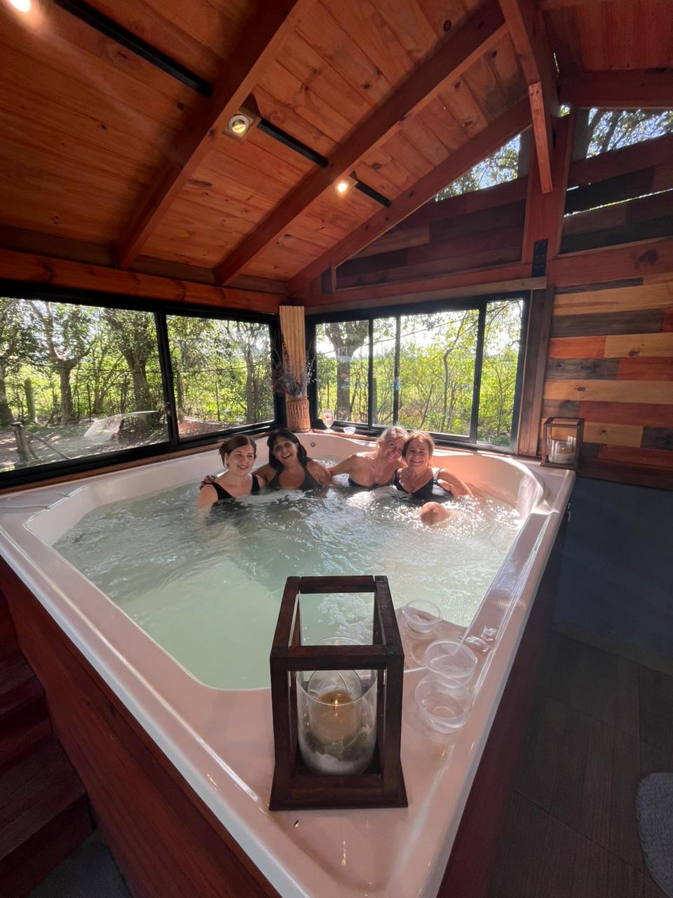 Grupo de mujeres relajándose en un jacuzzi, ambientado con velas.