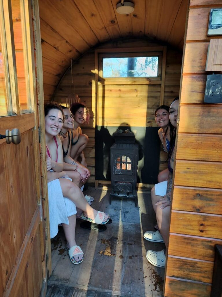 Grupo de mujeres dentro de un sauna, sonriendo a la cámara.